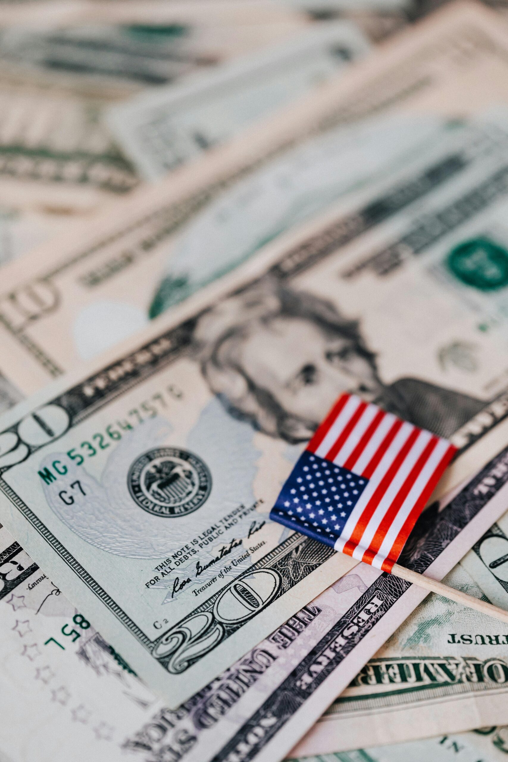 Close-up of US dollar bills with a small American flag, representing finance and economy.